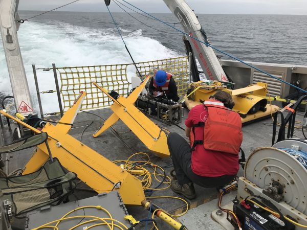 Jillian Maloney and Roslynn King on the fantail of a ship working on geophysical equipment