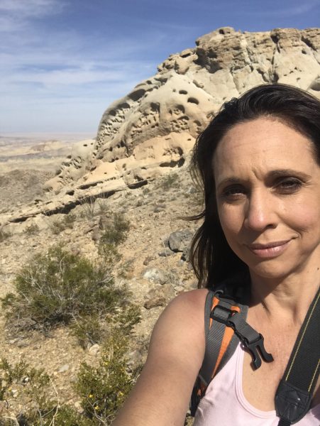 Jennifer Morton wearing a backpack standing in front of a sandstone outcrop