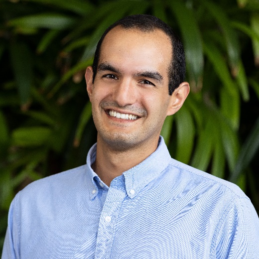 Trevor Jones wearing a blue button up collard shirt smiling