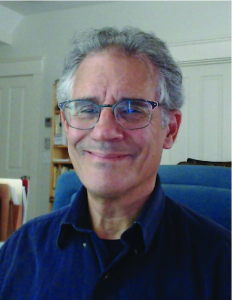 Dr. Ken Belitz wearing rectangular glasses and a dark blue collared shirt smiling at the camera