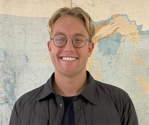 Brierton Sharp wearing round framed glasses smiling at the camera