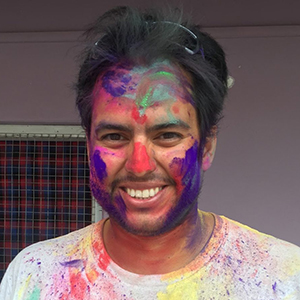 closeup of Rafael Almeida with Holi colors on his face.